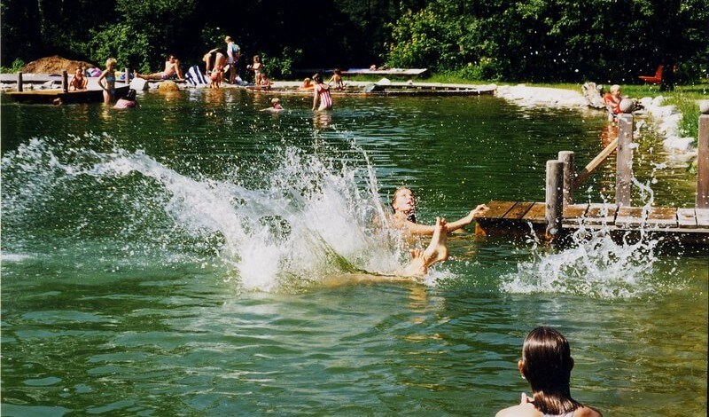 Kinder springen in den Badeteich